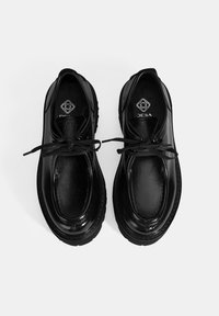 Zwarte leren schoenen met een glanzende afwerking, ronde neus, vetersluiting en een gestructureerde zwarte rubberen zool. Logo op de binnenzool.