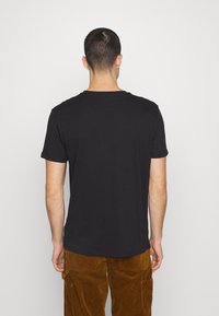 Black cotton T-shirt with short sleeves and a crew neckline, displayed from the back against a white background.