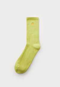 Grüne Baumwollsocke mit gerippter Struktur und gelbem Logo nahe der Oberseite. Verfügt über ein knöchellanges Design und eine glatte Oberfläche.