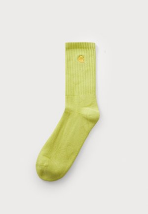 Green cotton sock with ribbed texture and a yellow logo near the top. Features a crew-length design and a smooth finish.