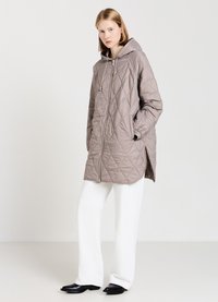 Giacca imbottita con cappuccio di un beige chiaro, con zip frontale, fessure laterali e una texture liscia e lucida. Abbinata a pantaloni bianchi a gamba larga e stivali neri.