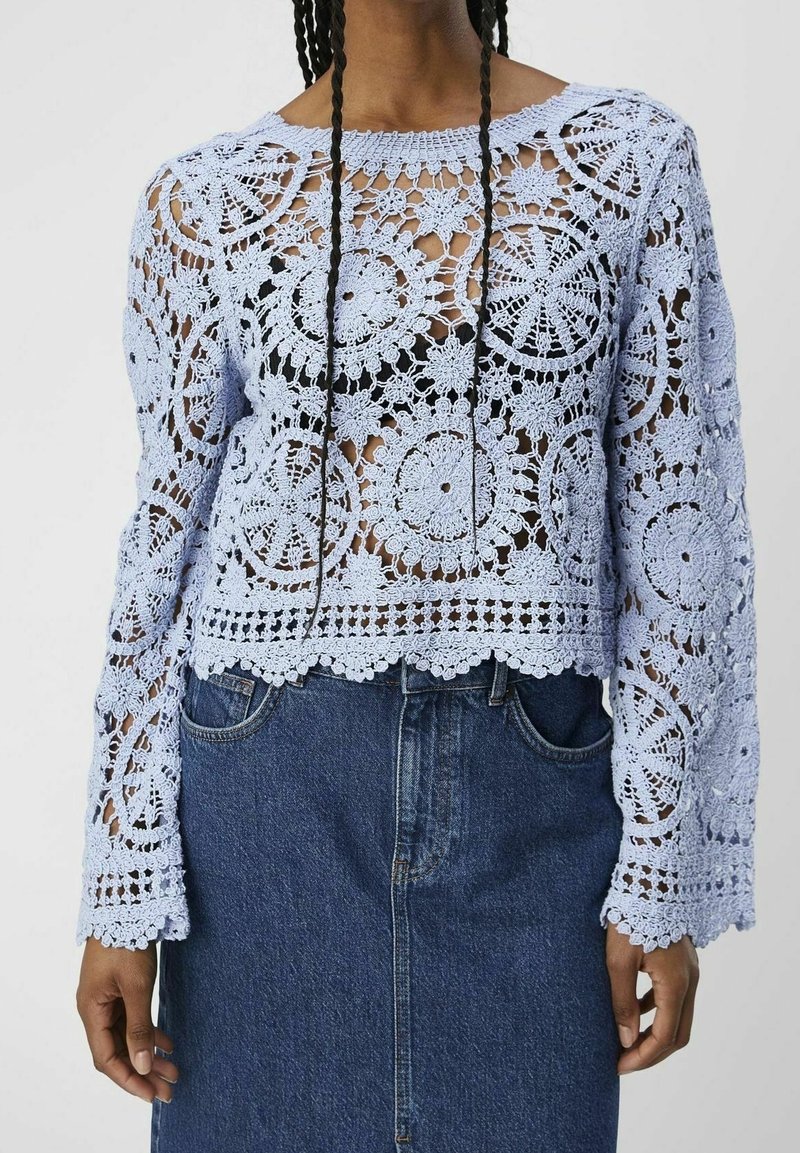 Haut à manches longues en dentelle fleurie crochetée bleu clair porté par-dessus un sous-t-shirt noir, associé à une jupe en denim bleu foncé taille haute.