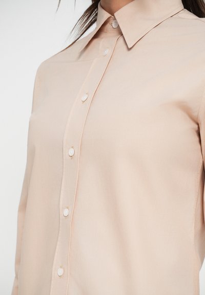 Light beige button-up shirt featuring a classic collar, smooth texture, and pearl-like buttons along the front placket.