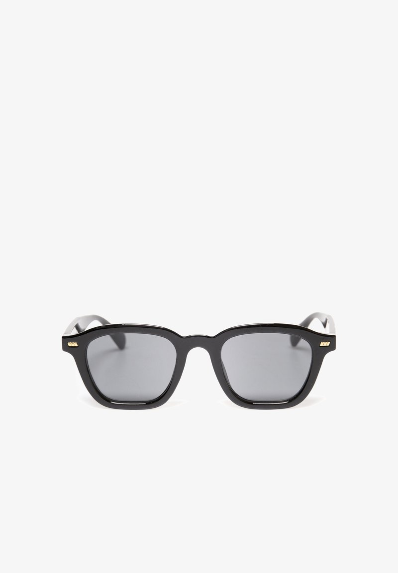 Mustad ristkülikukujulised prillid hallide läätsedega. Paks plastikraam kerge läikega. Kuldsed aktsendid templitel.