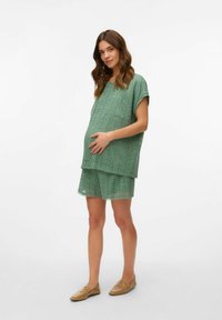 Conjunto de top de encaje verde menta y pantalones cortos a juego, con bordes con volantes y un corte holgado diseñado para la comodidad durante el embarazo.