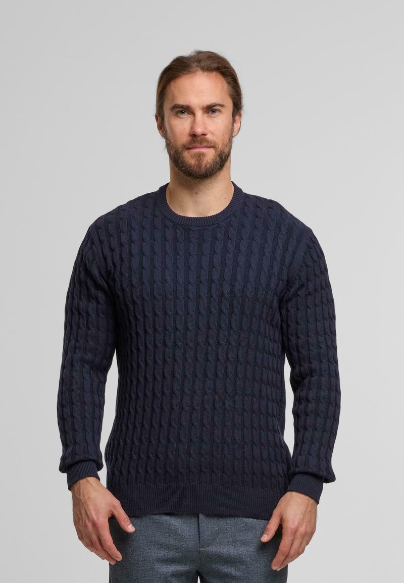 Maglione lavorato a maglia blu navy con un motivo a cavi testurizzati, colletto a giro e polsini a coste. Il tessuto sembra morbido e leggermente elasticizzato.