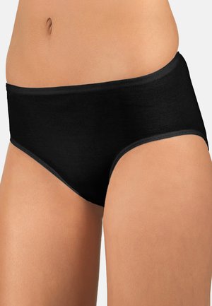 Woman wearing black high-waist cotton briefs showing midsection and upper legs against a plain background.