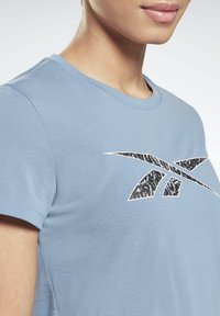 Ljusblå t-shirt i mjuk bomull med rund hals och korta ärmar. Har en svart och vit mönstrad logga på bröstet.