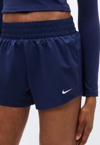 Σκούρα μπλε αθλητικά σορτς από λεία, ελαφριά υφάσματα με ελαστική μέση και λευκό λογότυπο Nike στη χαμηλότερη αριστερή πλευρά.