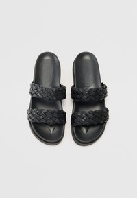 Svarte sklippersandaler med to flettede stropper, glatt plastfotseng og et buet såledesign for komfort. Ingen tilleggsglitter.