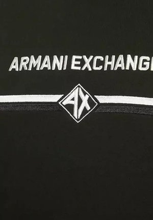Camiseta negra con el logo "ARMANI EXCHANGE" en blanco, con una franja horizontal blanca y un emblema en forma de diamante "AX".