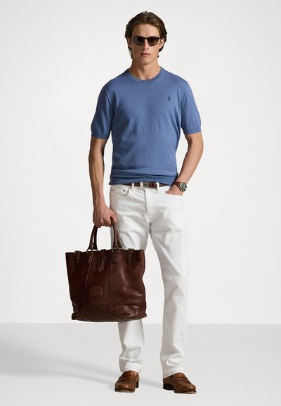 Pull en tricot bleu clair, pantalon en denim blanc et chaussures en cuir marron. Sac fourre-tout en cuir marron foncé avec doubles poignées et accents décoratifs.