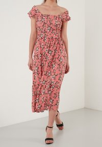 Vestido midi floral en rosa coral, con mangas de volantes sin hombros, cintura elástica y un dobladillo en capas con patrones florales oscuros.