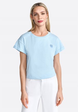 T-shirt en coton bleu clair avec des manches courtes roulées et un col rond. Présente un petit motif bleu brodé sur la poitrine.