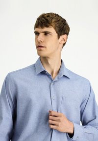 Jasnoniebieska koszula na guziki w drobną kratkę, z długimi rękawami, kieszenią na piersi i klasycznym kołnierzem. Gładka tekstura tkaniny.