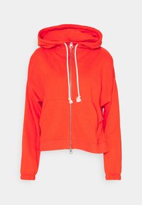 Sudadera corta de color rojo brillante con cremallera y cordones blancos, y bolsillo frontal tipo pouch, sobre un fondo claro liso.