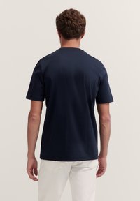 Navy blue cotton t-shirt with short sleeves, crew neck, and smooth texture, viewed from the back, simple design without patterns or accents.