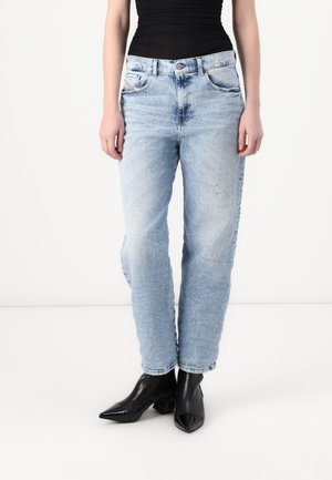 Light blue straight-leg jeans with fading and distressed details. Worn with black pointed-toe ankle boots, featuring a stacked heel.