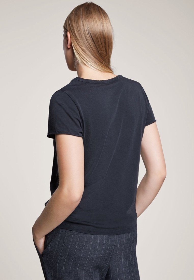 Chemise noire à manches courtes en tissu doux, coupe ajustée, encolure arrondie, design simple sans motifs ni accents visibles.