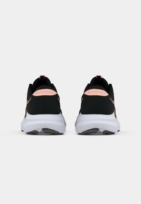 Ζευγάρι μαύρων και ροζ αθλητικών παπουτσιών από πίσω, με άσπρες σόλες και την επιγραφή "GEL-EXCITE 11" στις φτέρνες.