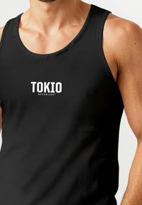 Schwarzes Tanktop mit rundem Halsausschnitt, das in der Mitte das weiße Logo "TOKIO NEVERLESS" aufweist. Glatte Textur und normale Passform.