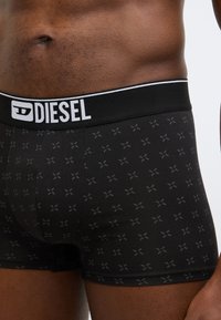 Fekete pamut boxerrövidnadrág, testre szabott kialakítással. Fekete-fehér "DIESEL" logós derékpánttal és finom keresztmintával.