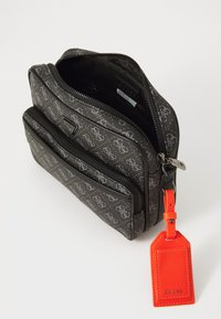 Compact gray patterned Guess pouch with black zipper, front pocket, and bright orange leather Guess tag attached to the side.