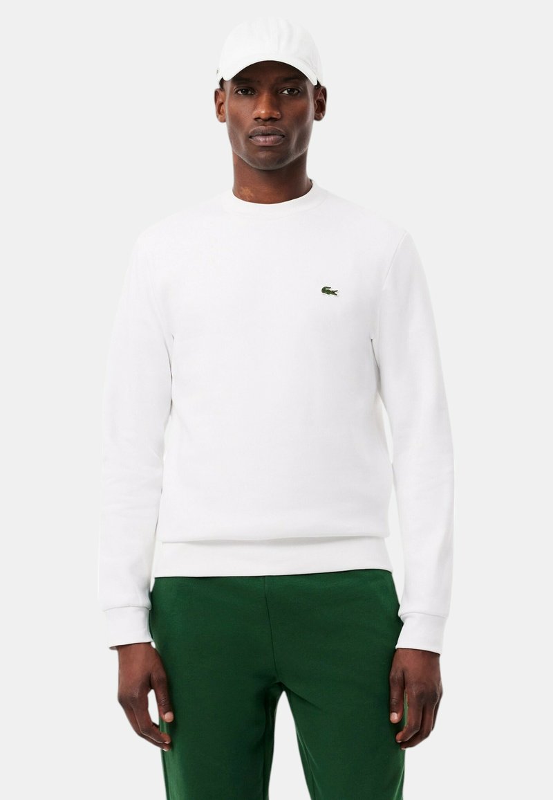 Felpa bianca in cotone, con collo tondo e maniche lunghe. Presenta un piccolo logo verde ricamato sul petto.