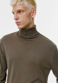 Brauner Rollkragenpullover aus geripptem Strickstoff, mit enganliegendem Design und hohem Halsausschnitt. Weiche Textur und nahtlose Verarbeitung.