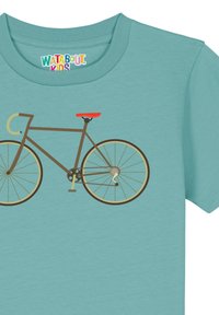 T-shirt turquoise avec un design imprimé de bicyclette marron, avec un siège orange et des roues beiges, sur un fond lisse et clair.