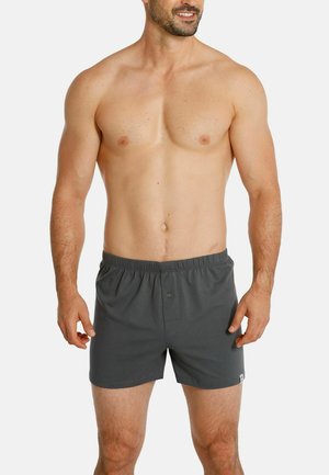 Graue Baumwollboxershorts mit einem elastischen Bund und einem einzelnen Knopfdetail, featuring einem kleinen Logo-Akzent auf der Seite. Keine Muster.