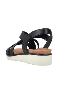 Sandale en cuir noir avec sangle réglable, détail tressé à l'avant, semelle intérieure rembourrée couleur tan, et semelle compensée blanche, inclinée pour montrer le côté et l'arrière.