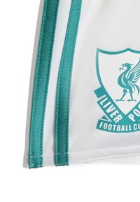 Biały materiał z dwoma pionowymi paskami w kolorze turkusowym i częściowym herbem Liverpool Football Club w kolorze turkusowym po prawej stronie.