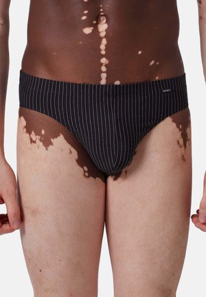 Schwarze gestreifte Slips aus elastischem Material, mit einem low-rise Design, weichem Bund und minimaler Markenkennzeichnung auf der Vorderseite.