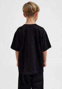 Sort bomulds T-shirt med afslappet pasform, korte ærmer og rund halsudskæring. Vinklen er fra bagsiden og viser et enkelt design.