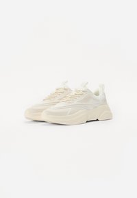 Chunky sneakers i off-white mesh og gummi, med et tekstureret design, tykk sål og løkke pull-tab på hælen.