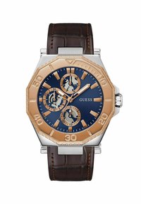 Reloj cronógrafo para hombre con un esfera azul marino, acentos en oro rosa, caja octagonal de acero inoxidable y correa de cuero marrón con un acabado texturizado.