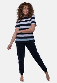 Raito ja vaaleansininen raidallinen lyhythihainen paita, yhdistettynä tummansinisiin yksivärisiin joustaviin jogger-housuihin. Pehmeä kangas, rento malli ja nilkkakuristukset.