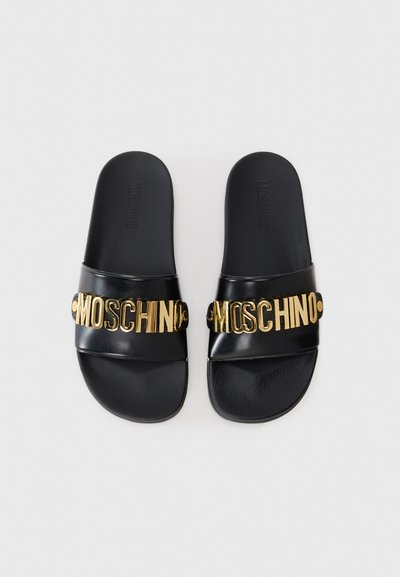  Sorte slidesandaler med en blank finish, der har et chunky guld "MOSCHINO" logo på remmen. Tekstureret fodseng for komfort.