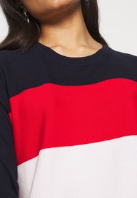 Tröja med horisontella ränder i marinblått, rött och vitt. Stickad struktur med rundad hals. Lätt tyg och mjuk yta.