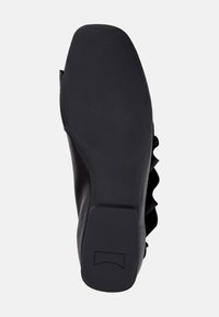 Zwarte schoenenzool met een gestructureerd grip patroon, voorzien van een afgeronde neus en golvende accenten langs de zijkanten voor extra detail.