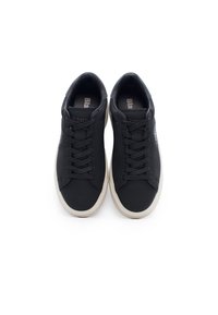 Sneakers nere con tomaia sintetica liscia, punta rotonda, lacci piatti e suola in gomma beige a contrasto; presentano il logo sui lati.