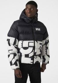 Chaqueta acolchada con un esquema de color blanco y negro, impresiones gráficas audaces, cierre con cremallera en la parte delantera y capucha. Fabricada con un material sintético suave.