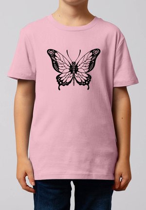 Enfant portant un t-shirt rose avec un motif détaillé de papillon noir centré sur la poitrine, sur un fond uni.