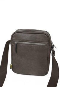 Bolso mensajero de cuero marrón con forma rectangular plana, correa ajustable, bolsillo con cremallera en la parte frontal y una pequeña etiqueta de marca amarilla.