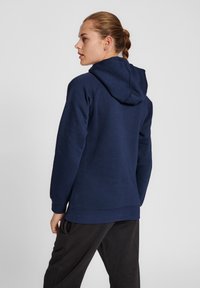 Granatowa bluza z kapturem, z długimi rękawami i ściągaczem przy rękawach. Charakteryzuje się luźnym krojem i miękką fakturą materiału.