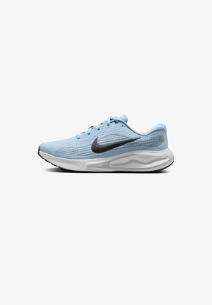 Zapatilla deportiva de color azul claro con parte superior texturizada, logo de swoosh negro, media suela blanca y suela de goma negra. Presenta un diseño con cordones.