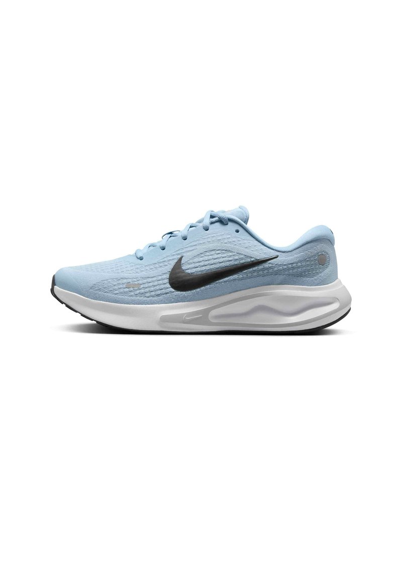 Zapatilla deportiva de color azul claro con parte superior texturizada, logo de swoosh negro, media suela blanca y suela de goma negra. Presenta un diseño con cordones.