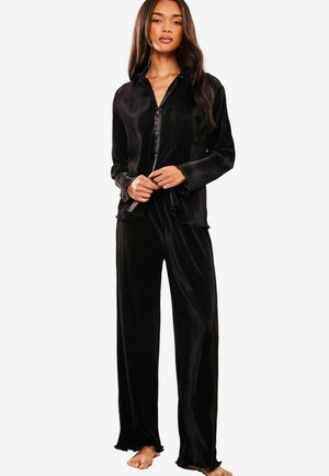 Musta satiininen pyjama-setti, joka sisältää napitettavan paidan, jossa on kaulus ja pitkät hihat, sekä leveälahkeiset housut, joissa on hieno ribbikuvio.