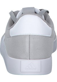 Grau-weißer Sneaker mit einem Obermaterial aus Wildleder und Synthetik, gepolstertem Kragen und flacher weißer Sohle mit strukturiertem Profil und Logo-Detail.